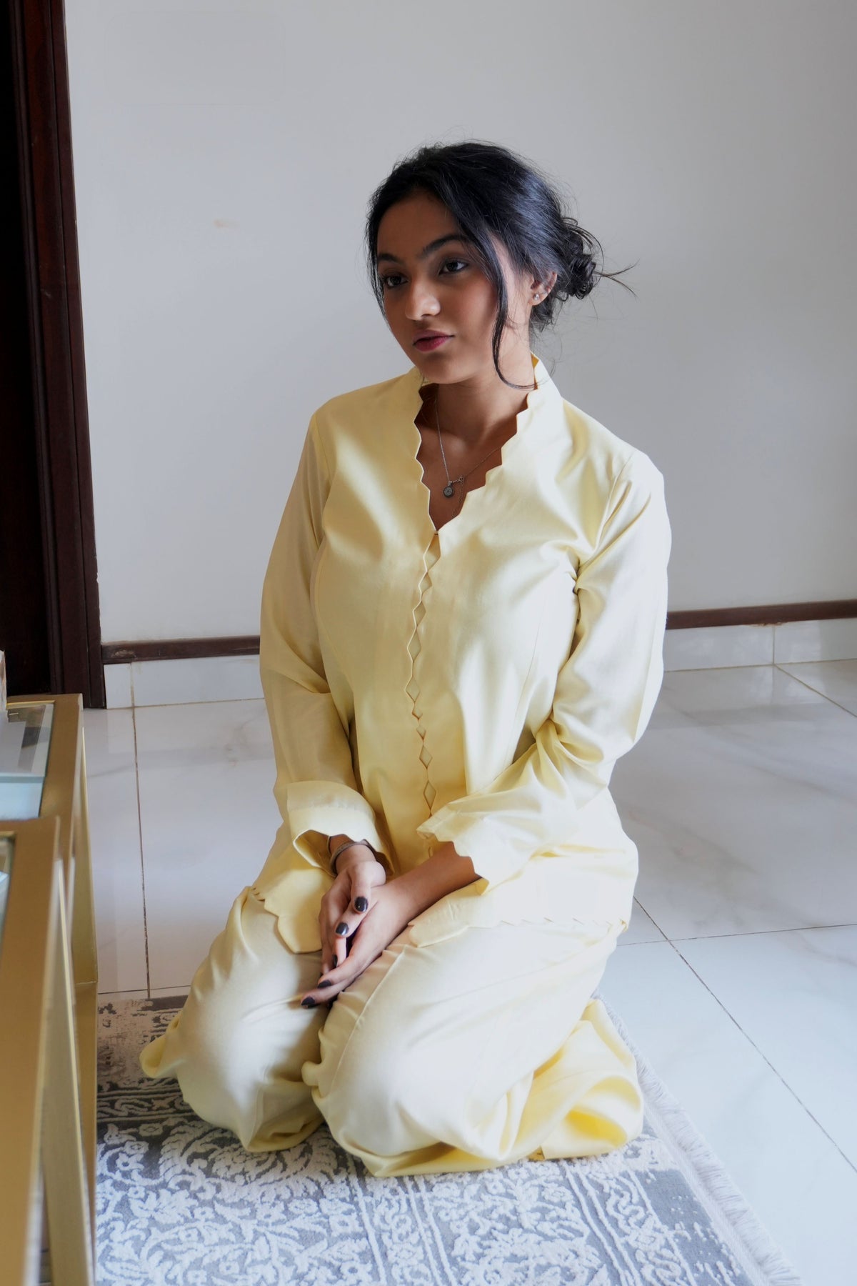 Alisho Buttercream shirt and bootcut pants set worn by a model seated