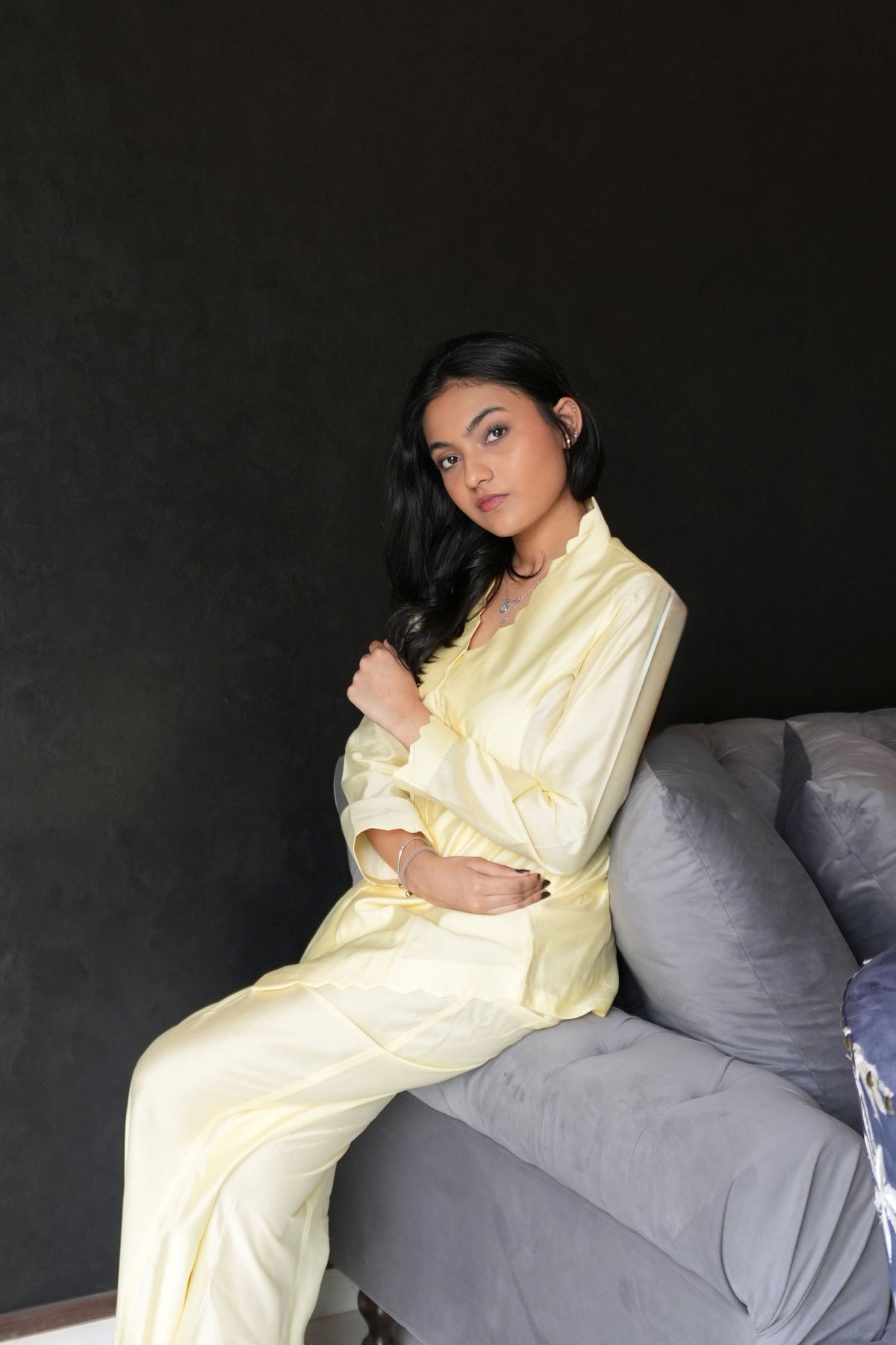 Alisho Buttercream shirt and bootcut pants worn by a model seated on sofa 